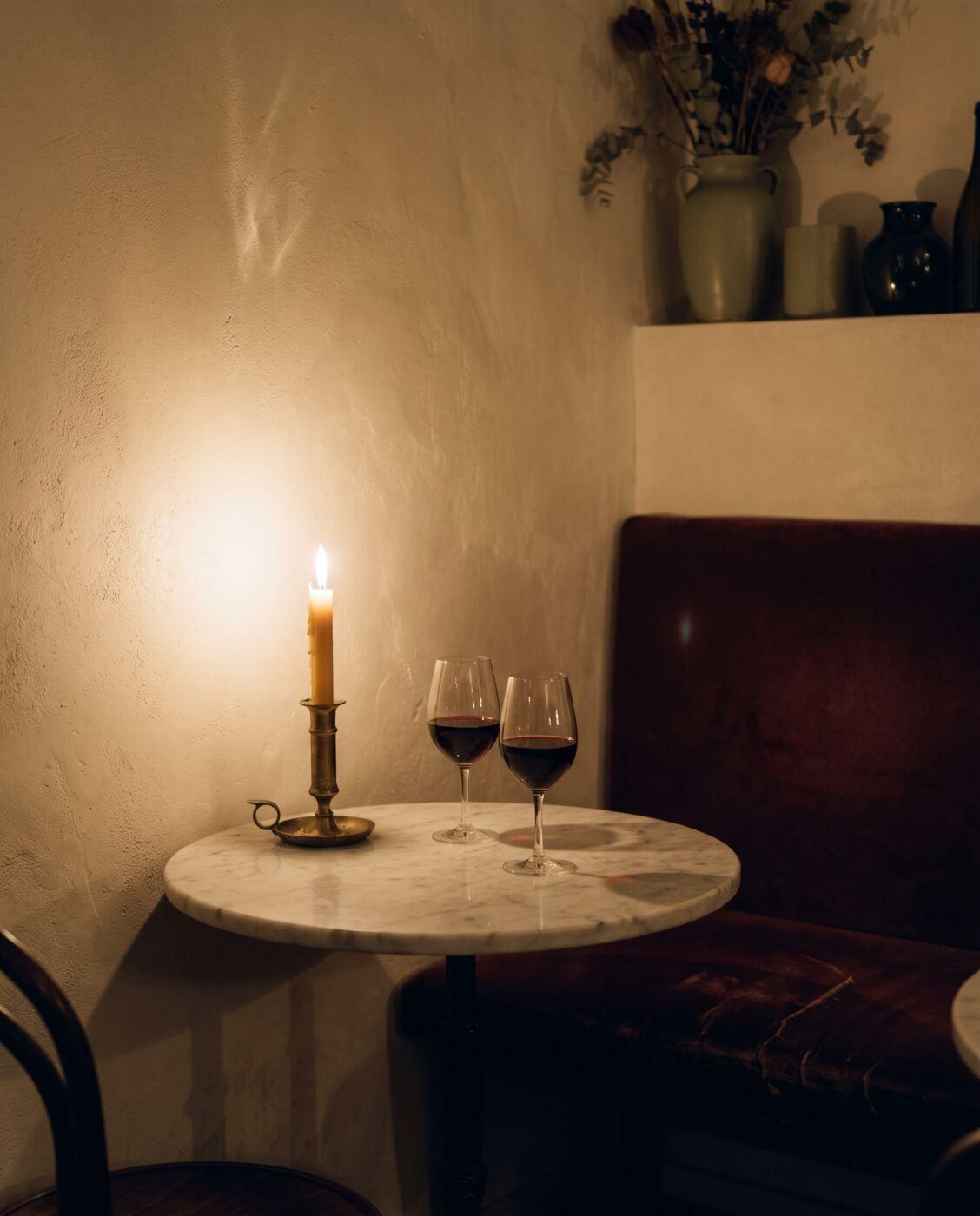 Rincón de bar a la luz de una vela con dos copas de vino